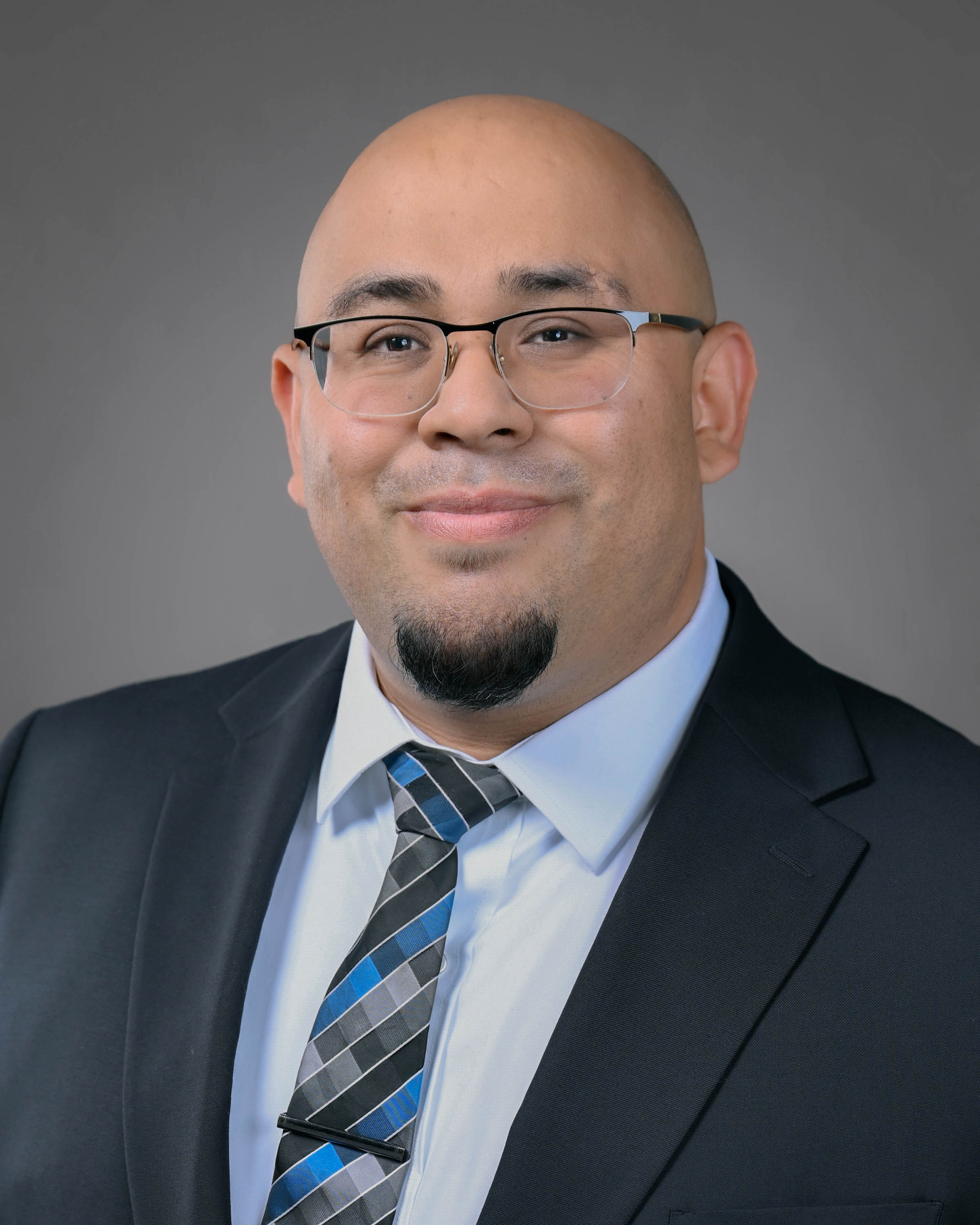 Clean cut man in a suit with a goatee.